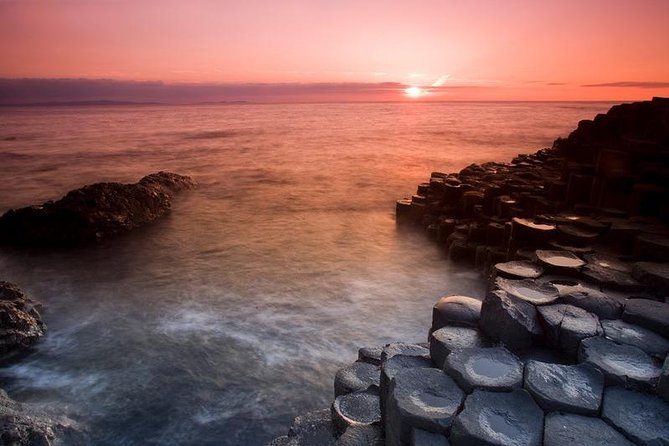 Basalt columns at the Giant&rsquo;s Causeway with the sun low over the sea